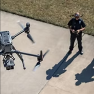 Professional drone in flight with operator controlling aerial surveillance equipment outdoors.