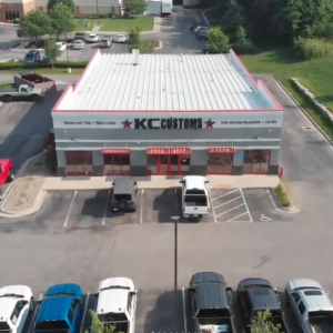 KC Customs commercial building aerial view with parking lot and red accents.