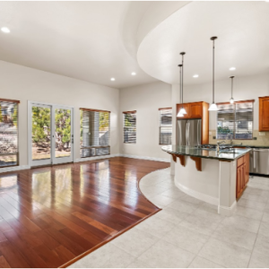 Modern open-concept kitchen and living room with hardwood floors, granite island, and large windows.