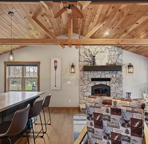 Rustic living room with stone fireplace, vaulted wood beams, and cozy seating.