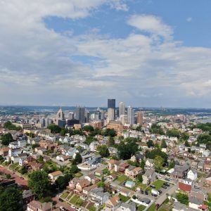 Aerial view of city skyline, residential neighborhood, green hills, and urban landscape.