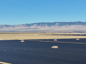 Aerial View Of Solar Farm Snow Capped Mountains