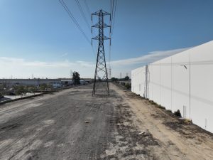 Industrial Gravel Road Beside Warehouse and Power Lines