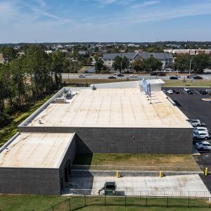 Aerial view of modern commercial building with large parking lot in urban business district.